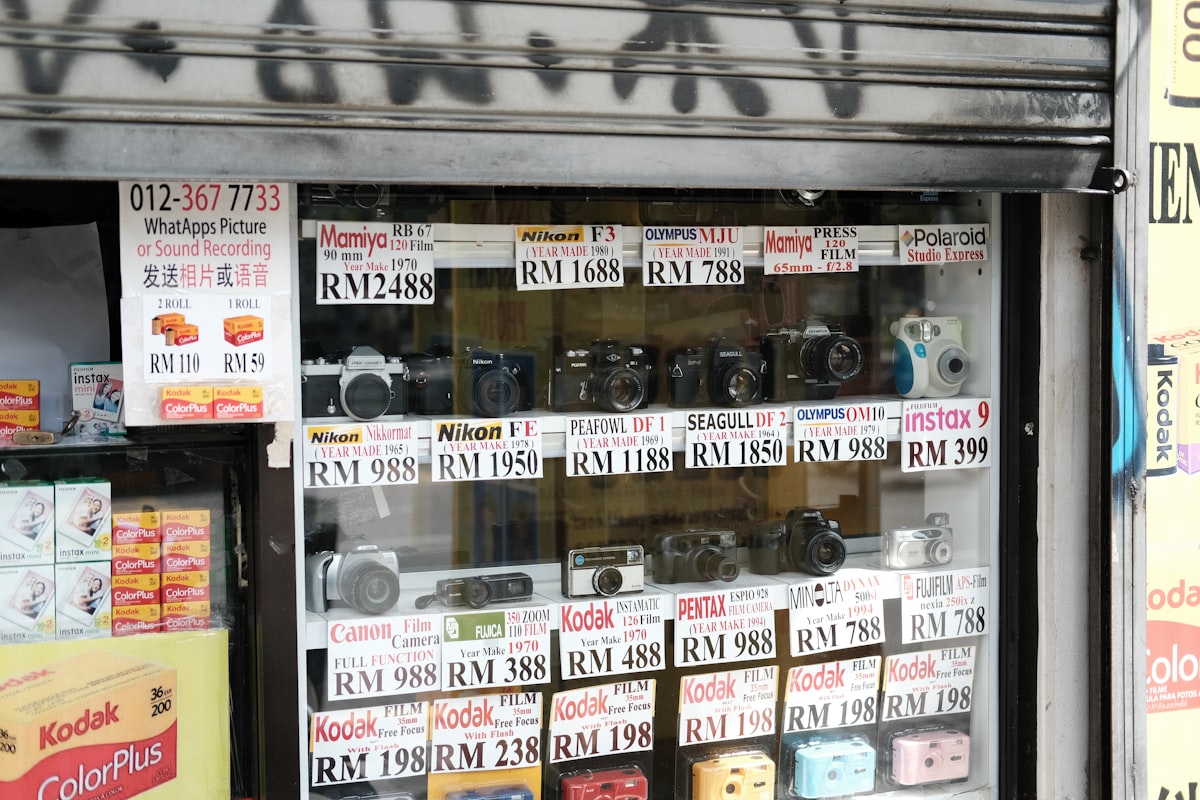A camera store storefront window display with price tags on used cameras