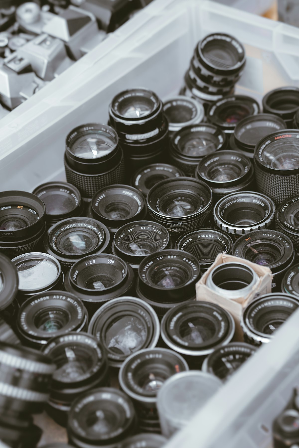 A crate overflowing with a large collection of camera lenses