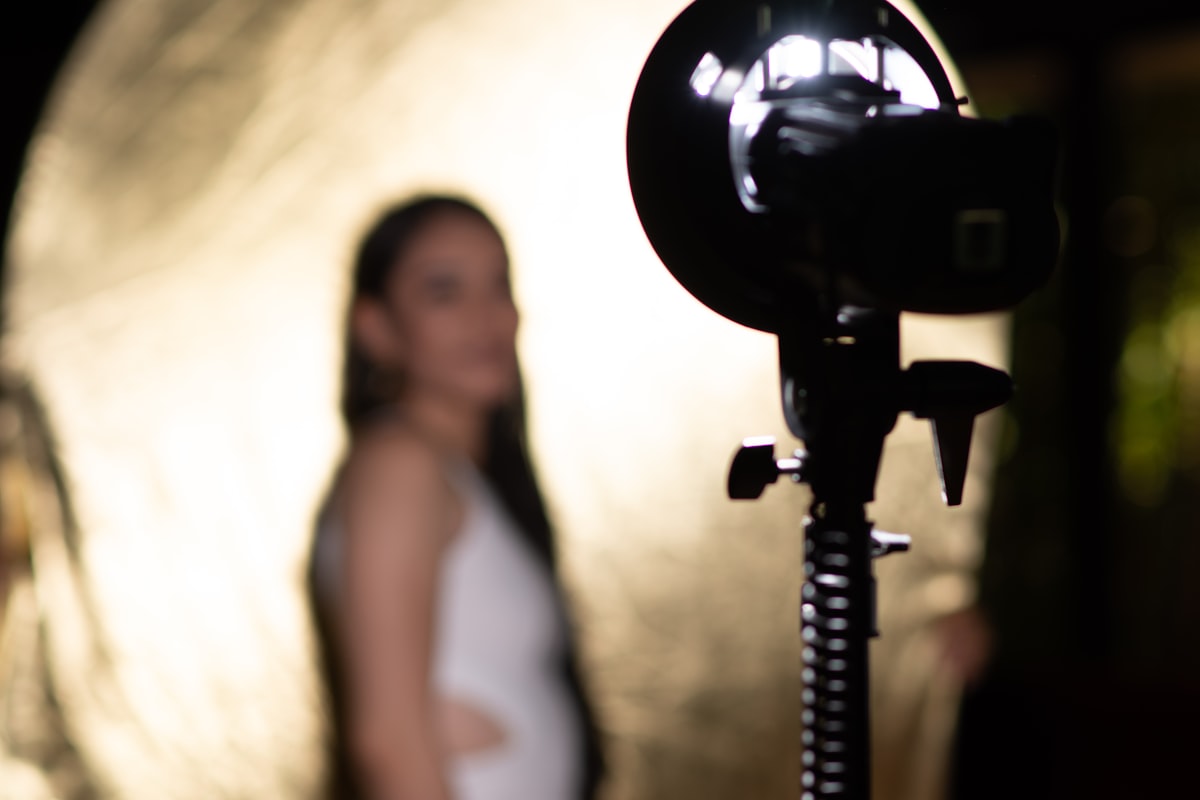 A studio flash on a light stand with a subject blurred in the background