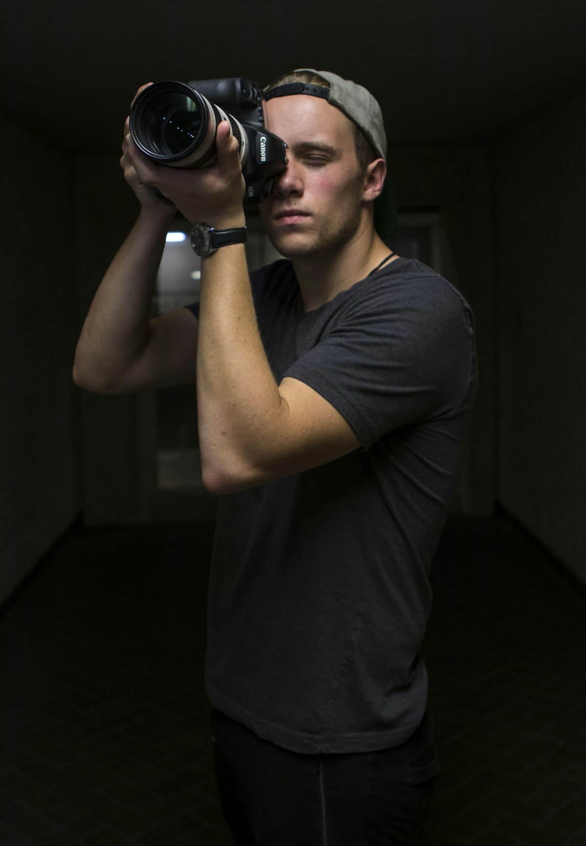 A photographer holding a DSLR camera with a telephoto lens up to their eye