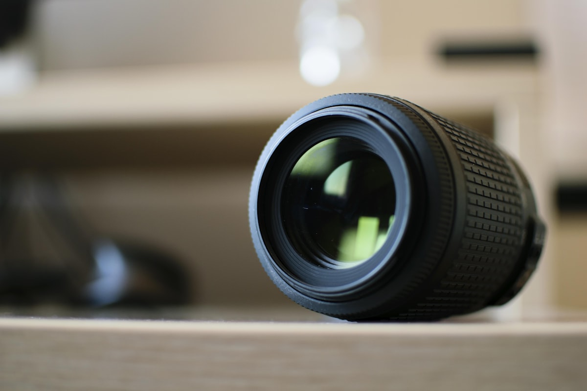 A telephoto zoom lens resting alone on a wooden shelf