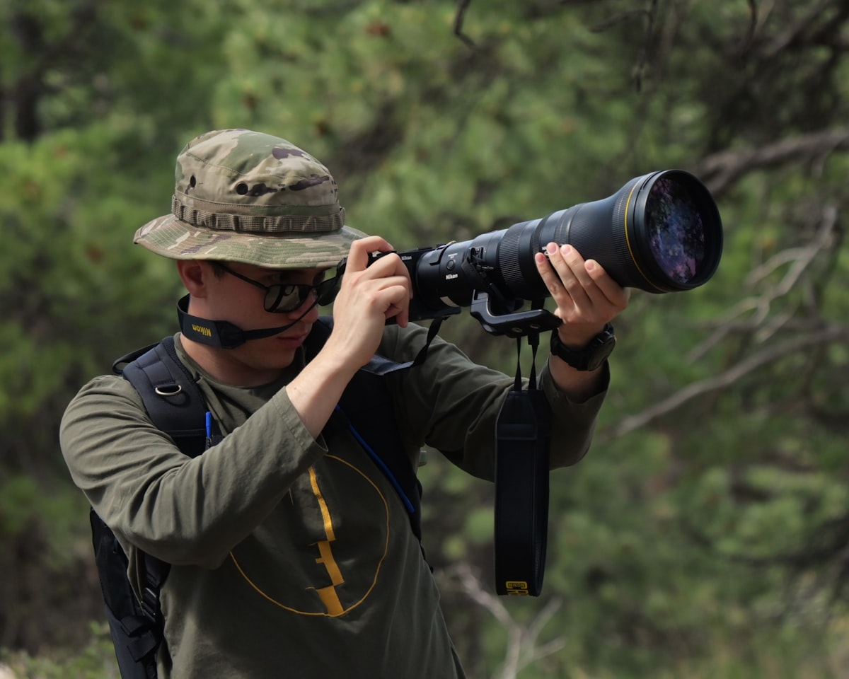 A wildlife photographer using a large telephoto lens outdoors